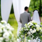 Outdoor wedding with flowers, bride and groom facing away