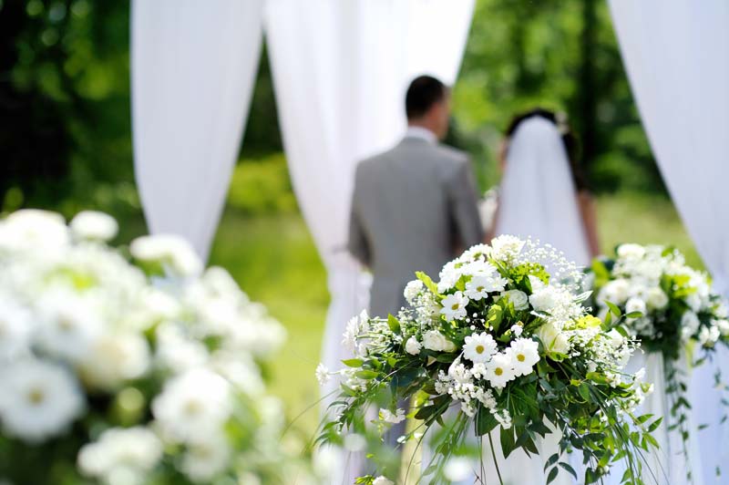 Outdoor wedding with flowers, bride and groom facing away